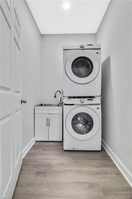 3502 Goodwin Neck Rd, Yorktown, VA 23692 - washroom featuring stacked washing machine and dryer, cabinet space, baseboards, and light wood finished floors