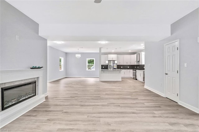 3502 Goodwin Neck Rd, Yorktown, VA 23692 - unfurnished living room with a glass covered fireplace, light wood-style floors, baseboards, recessed lighting, and a chandelier