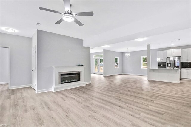 3502 Goodwin Neck Rd, Yorktown, VA 23692 - unfurnished living room with light wood-style flooring, plenty of natural light, a glass covered fireplace, and baseboards