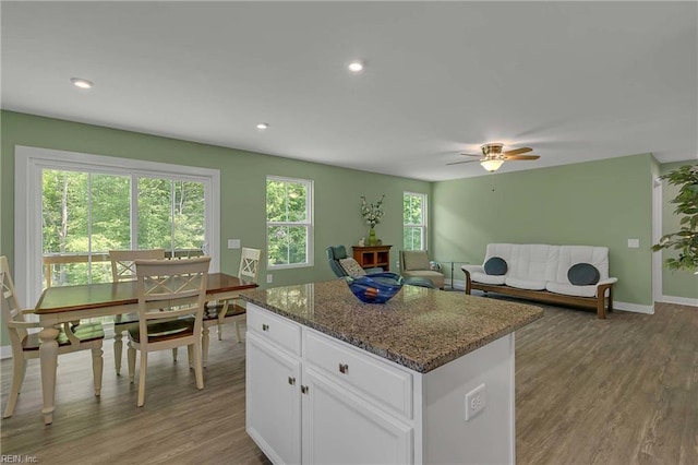 6945 Healy Ave, Gloucester, VA 23061 - kitchen with a center island, light wood-style flooring, white cabinets, ceiling fan, and dark stone countertops