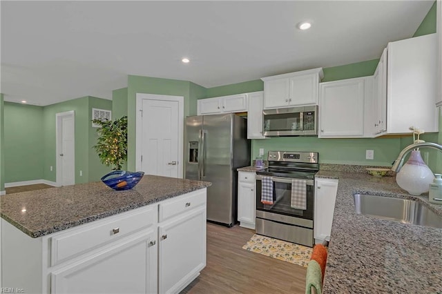 6945 Healy Ave, Gloucester, VA 23061 - kitchen with appliances with stainless steel finishes, a sink, white cabinetry, dark stone counters, and wood finished floors