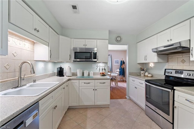 2004 Convoy Ct, Virginia Beach, VA 23454 - kitchen with stainless steel appliances, under cabinet range hood, white cabinetry, tasteful backsplash, and light countertops