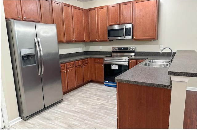 932 Southmoor Dr Unit 105, Virginia Beach, VA 23455 - kitchen with stainless steel appliances, a sink, dark countertops, and light wood-type flooring