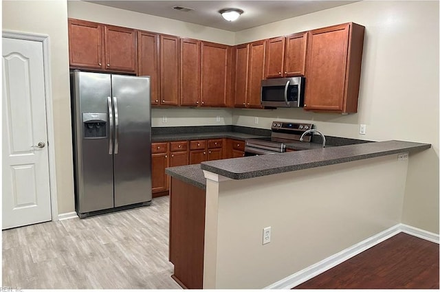 932 Southmoor Dr Unit 105, Virginia Beach, VA 23455 - kitchen with appliances with stainless steel finishes, light wood-style flooring, dark countertops, and a peninsula