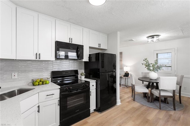 3421 Stancil St, Virginia Beach, VA 23452 - kitchen with black appliances, light wood-style flooring, backsplash, white cabinetry, and a textured ceiling