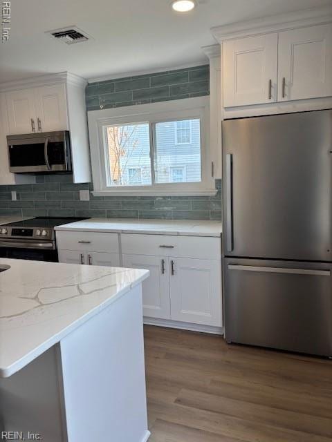 913 B St, Virginia Beach, VA 23451 - kitchen featuring appliances with stainless steel finishes, white cabinetry, decorative backsplash, light stone counters, and wood finished floors