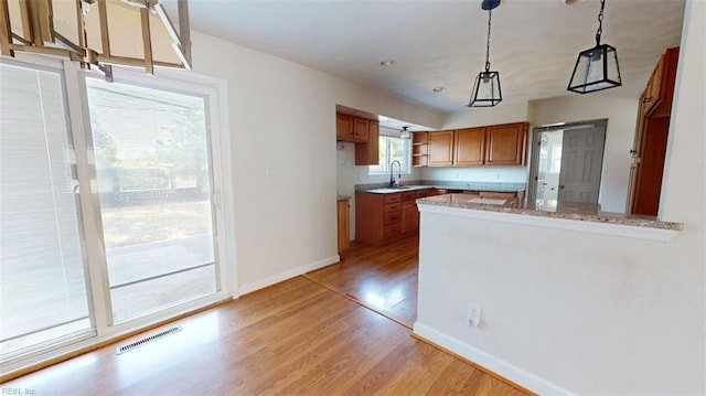 400 Ticonderoga Rd, Virginia Beach, VA 23462 - kitchen with brown cabinets, a peninsula, light wood finished floors, open shelves, and pendant lighting