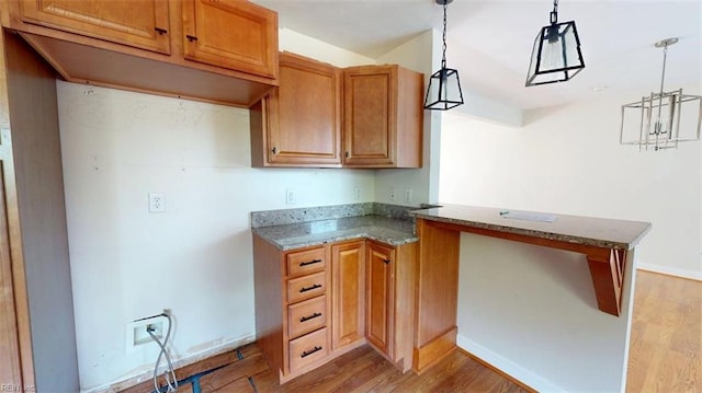 400 Ticonderoga Rd, Virginia Beach, VA 23462 - kitchen featuring light wood finished floors, a peninsula, stone countertops, hanging light fixtures, and brown cabinetry