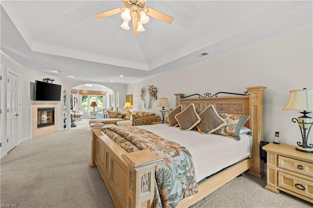 1604 Tether Keep, Virginia Beach, VA 23454 - bedroom featuring arched walkways, light carpet, a tray ceiling, a tiled fireplace, and recessed lighting