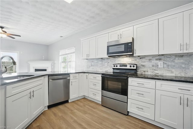 5217 Maracas Arch Arch Unit 50, Virginia Beach, VA 23462 - kitchen with appliances with stainless steel finishes, white cabinets, decorative backsplash, light wood-style flooring, and dark stone countertops
