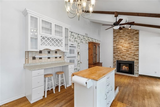 318 Hearthstone Way, Newport News, VA 23608 - kitchen featuring white double oven, white cabinetry, a tile fireplace, beam ceiling, and a ceiling fan