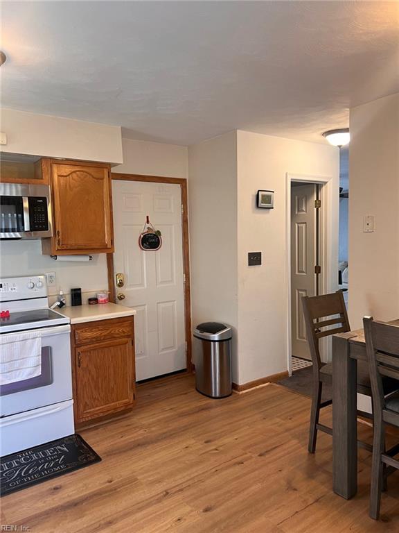 222 Greenfield Cres, Suffolk, VA 23434 - kitchen featuring stainless steel microwave, white electric range oven, brown cabinetry, light wood finished floors, and light countertops