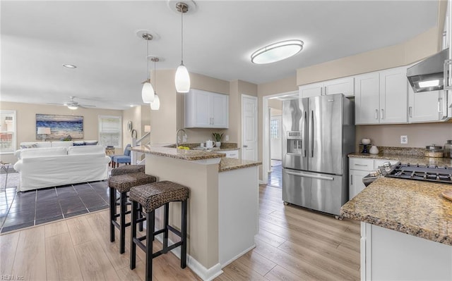 1304 Glen Burnie Ct, Virginia Beach, VA 23454 - kitchen with stainless steel fridge with ice dispenser, a peninsula, light stone countertops, a kitchen bar, and light wood-style floors