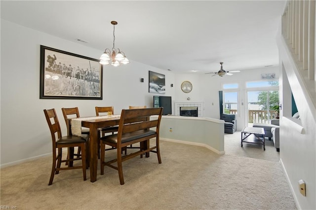 1039 Little Bay Ave, Norfolk, VA 23503 - dining area with light colored carpet, a fireplace, a ceiling fan, a chandelier, and stairs