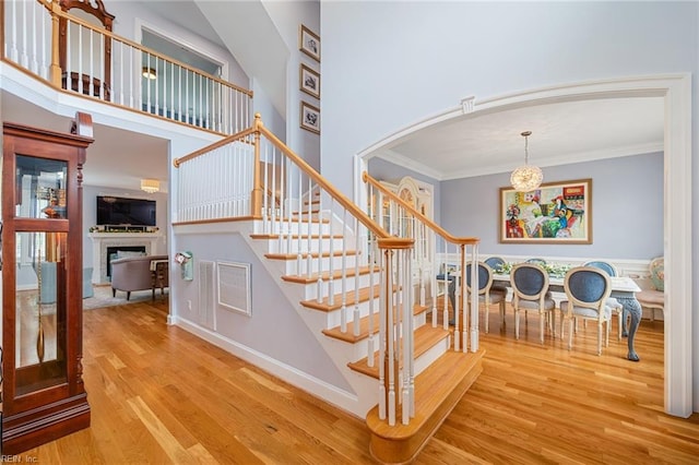 6003 Spinnaker Cove Ct, Suffolk, VA 23435 - stairs featuring wood finished floors, a fireplace, ornamental molding, arched walkways, and a chandelier