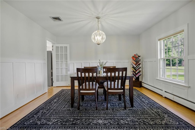 2400 Deerfield Cres, Chesapeake, VA 23321 - dining space with a baseboard radiator, a chandelier, a decorative wall, light wood-type flooring, and a wainscoted wall