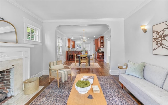 418 Massachusetts Ave, Norfolk, VA 23508 - living room with arched walkways, dark wood finished floors, a brick fireplace, a chandelier, and crown molding