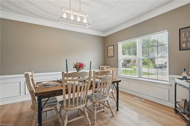 305 Ginkgo Ct, Suffolk, VA 23435 - dining room featuring crown molding, light wood-style floors, a wainscoted wall, and a decorative wall