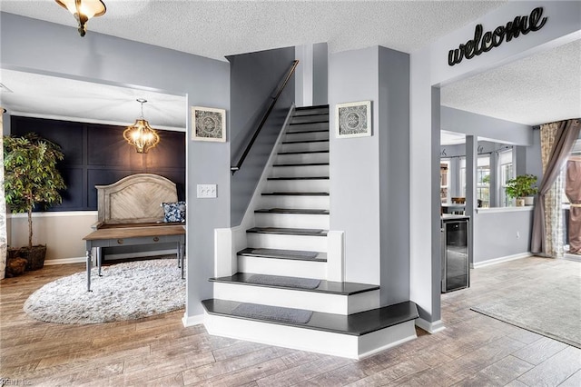 1205 Woods Way, Chesapeake, VA 23323 - staircase with a textured ceiling, wood finished floors, beverage cooler, and a chandelier