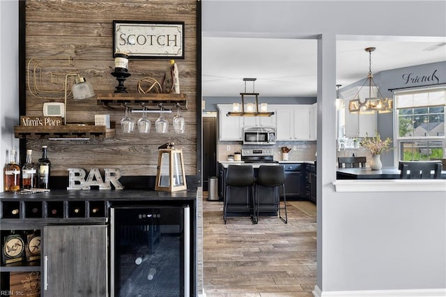 1205 Woods Way, Chesapeake, VA 23323 - indoor dry bar featuring beverage cooler, stainless steel microwave, light wood-type flooring, tasteful backsplash, and a chandelier