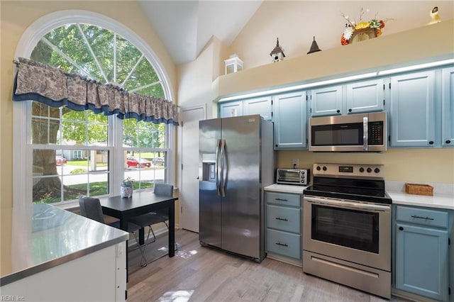 1013 Winged Foot Ct Unit A, Chesapeake, VA 23320 - kitchen featuring appliances with stainless steel finishes, vaulted ceiling, light wood-style flooring, light countertops, and blue cabinets