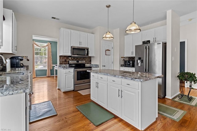 2000 Kelsey Bay Ct, Chesapeake, VA 23323 - kitchen featuring appliances with stainless steel finishes, a kitchen island, white cabinets, and backsplash