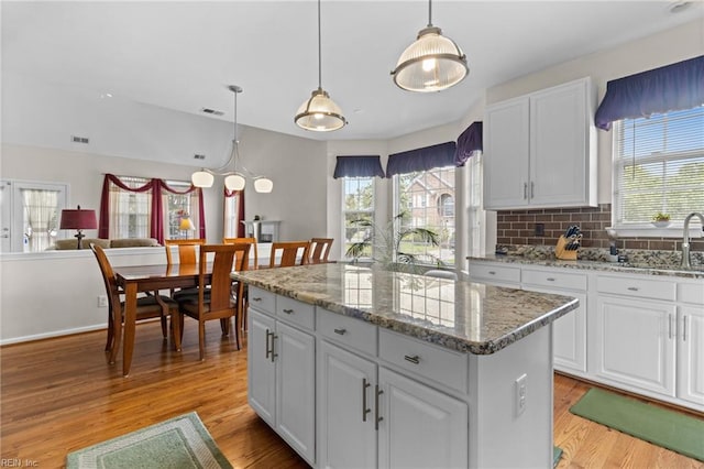 2000 Kelsey Bay Ct, Chesapeake, VA 23323 - kitchen featuring a kitchen island, light wood-style flooring, white cabinetry, and decorative backsplash