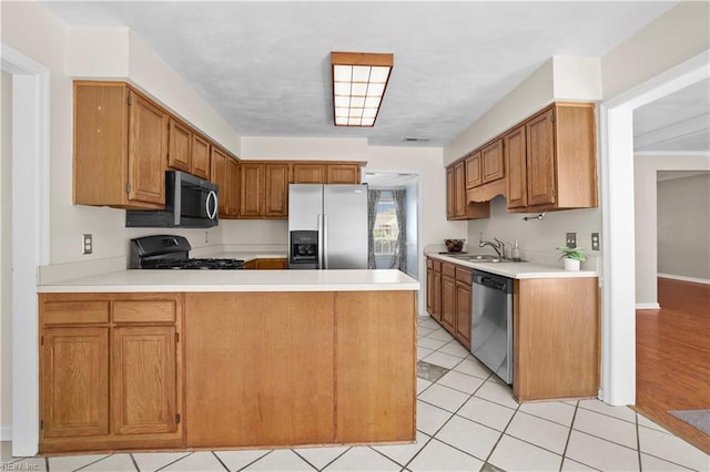 2505 Castle Hill Ct, Virginia Beach, VA 23454 - kitchen with stainless steel appliances, light countertops, a peninsula, light tile patterned floors, and brown cabinets