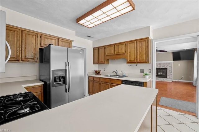 2505 Castle Hill Ct, Virginia Beach, VA 23454 - kitchen featuring stainless steel refrigerator with ice dispenser, light countertops, stovetop, brown cabinets, and a glass covered fireplace