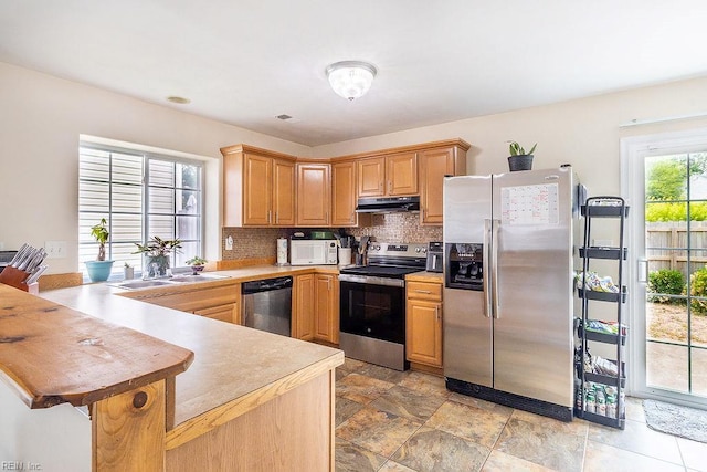 5537 Port Royal Dr, Virginia Beach, VA 23462 - kitchen featuring appliances with stainless steel finishes, under cabinet range hood, backsplash, a peninsula, and light stone finish floors