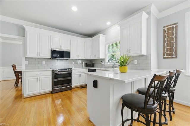 20517 Madison Ct, Smithfield, VA 23430 - kitchen with stainless steel appliances, ornamental molding, a breakfast bar area, a peninsula, and white cabinets