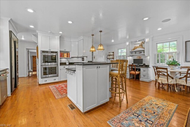 537 Cavalier Dr, Virginia Beach, VA 23451 - kitchen featuring stainless steel double oven, dark countertops, white cabinets, a breakfast bar, and light wood-type flooring