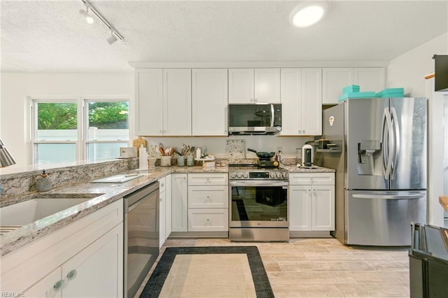 1509 Cypress Ave, Virginia Beach, VA 23451 - kitchen with appliances with stainless steel finishes, white cabinets, light stone countertops, rail lighting, and a textured ceiling