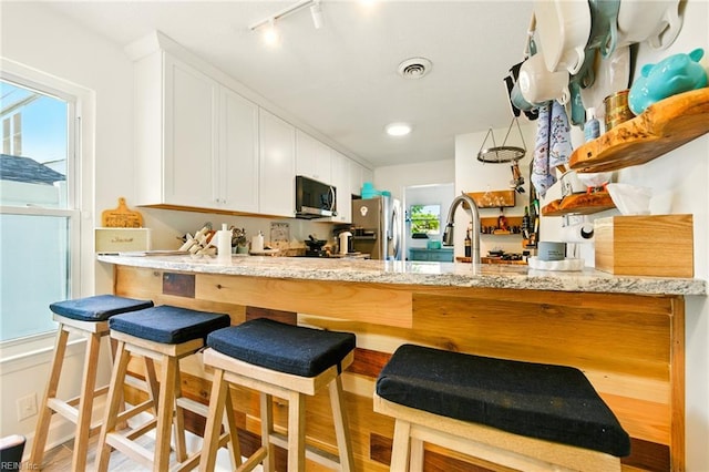 1509 Cypress Ave, Virginia Beach, VA 23451 - kitchen featuring appliances with stainless steel finishes, a peninsula, rail lighting, white cabinets, and wood finished floors