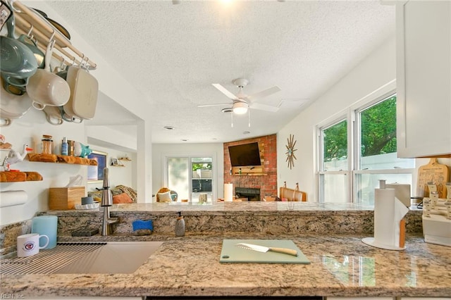 1509 Cypress Ave, Virginia Beach, VA 23451 - kitchen featuring a textured ceiling, a fireplace, light stone counters, and ceiling fan
