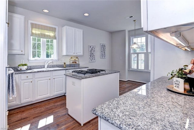 6667 Rexford Ln, Williamsburg, VA 23188 - kitchen with white gas stovetop, a kitchen island, dark wood-style flooring, white cabinets, and recessed lighting