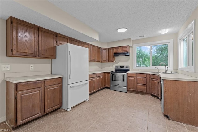 890 Brompton Ct, Newport News, VA 23608 - kitchen with electric stove, under cabinet range hood, freestanding refrigerator, brown cabinets, and a textured ceiling
