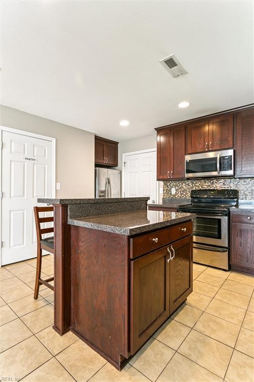 305 Roane Dr, Hampton, VA 23669 - kitchen with appliances with stainless steel finishes, light tile patterned floors, a kitchen island, backsplash, and recessed lighting