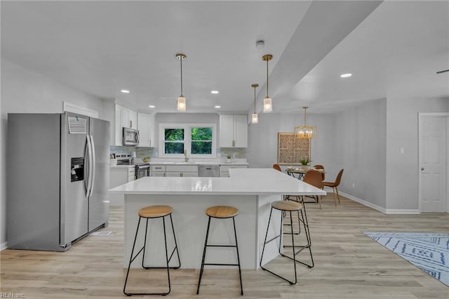 1226 Penniman Rd, Williamsburg, VA 23185 - kitchen featuring appliances with stainless steel finishes, white cabinetry, a breakfast bar, decorative backsplash, and light wood finished floors