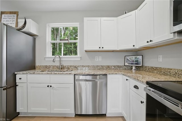 116 B St, Moyock, NC 27958 - kitchen featuring stainless steel appliances, white cabinets, light stone counters, and light wood-style flooring