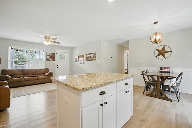 116 B St, Moyock, NC 27958 - kitchen with light wood-type flooring, a kitchen island, ceiling fan, open floor plan, and light stone counters
