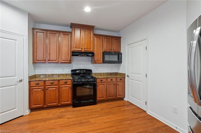 4048 Coronation, Williamsburg, VA 23188 - kitchen featuring black appliances, under cabinet range hood, brown cabinetry, dark stone countertops, and light wood-style floors