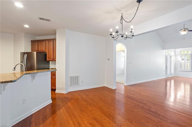 4048 Coronation, Williamsburg, VA 23188 - kitchen featuring freestanding refrigerator, brown cabinets, a kitchen bar, arched walkways, and dark wood-type flooring