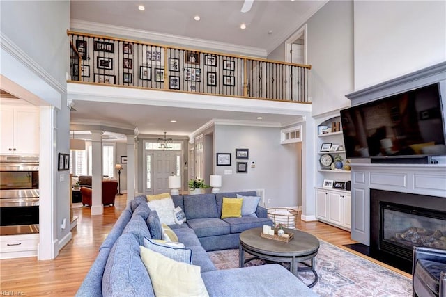 1808 John Hancock Rd, Williamsburg, VA 23185 - living area with crown molding, ornate columns, a towering ceiling, light wood-type flooring, and a fireplace with flush hearth