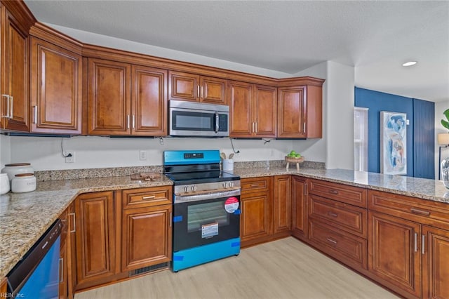 3520 S Warwick Cir, Norfolk, VA 23513 - kitchen with appliances with stainless steel finishes, brown cabinetry, light stone counters, and light wood-style floors