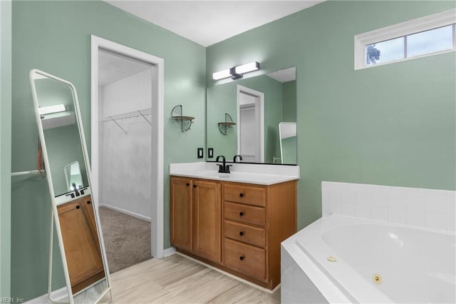 1028 Cathedral Dr, Suffolk, VA 23434 - bathroom featuring vanity, a jetted tub, a walk in closet, and wood finished floors