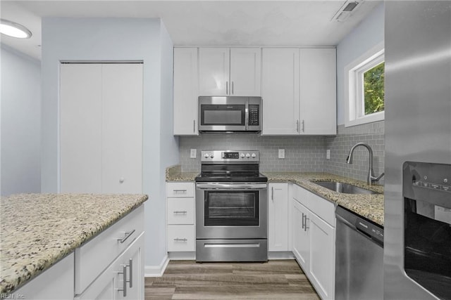 1833 Darville Dr, Hampton, VA 23663 - kitchen featuring appliances with stainless steel finishes, wood finished floors, white cabinets, and tasteful backsplash