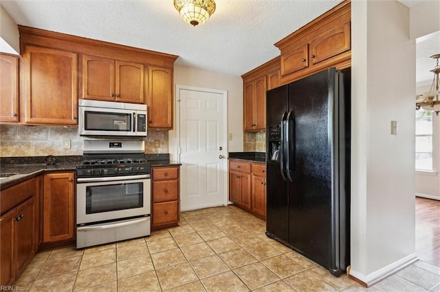 208 Sherbrooke Dr, Newport News, VA 23602 - kitchen with stainless steel appliances, decorative backsplash, brown cabinetry, light tile patterned flooring, and a textured ceiling