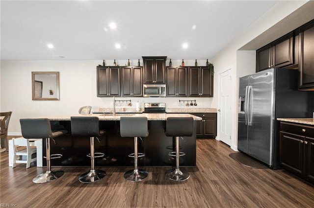 958 Olmstead St, Chesapeake, VA 23323 - kitchen featuring appliances with stainless steel finishes, a kitchen island with sink, a breakfast bar area, dark wood-style flooring, and dark brown cabinets