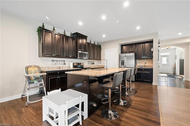 958 Olmstead St, Chesapeake, VA 23323 - kitchen featuring stainless steel appliances, arched walkways, a center island with sink, dark wood-style flooring, and a breakfast bar